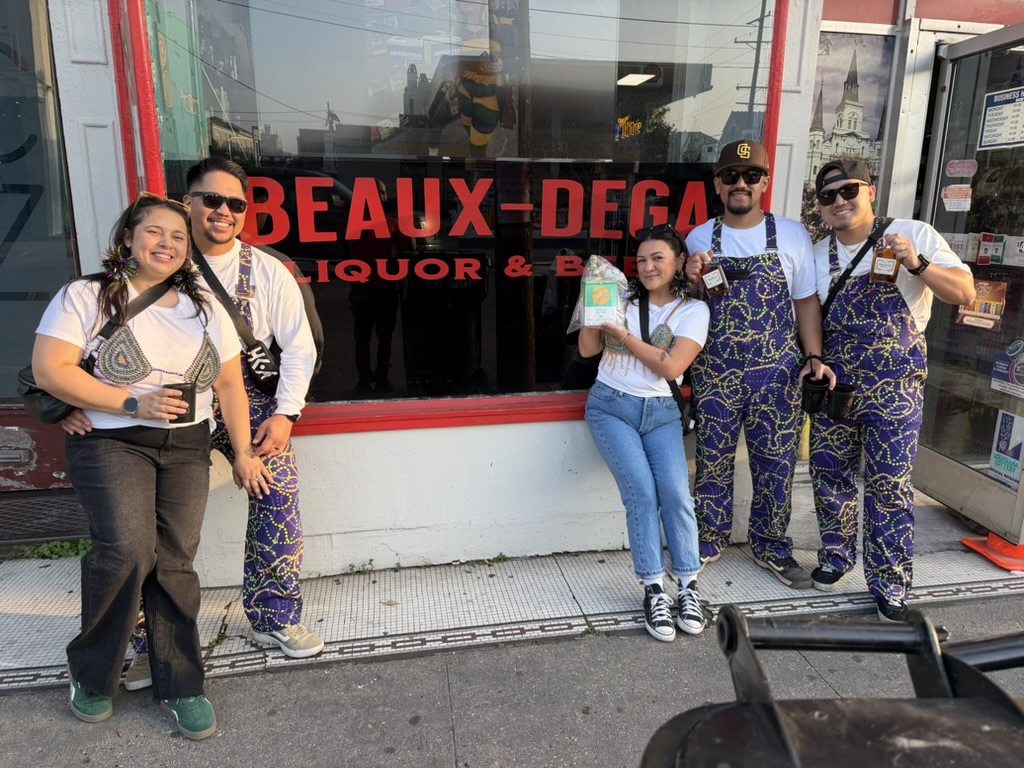 A group posing outside Beaux-dega’s red-lettered storefront window